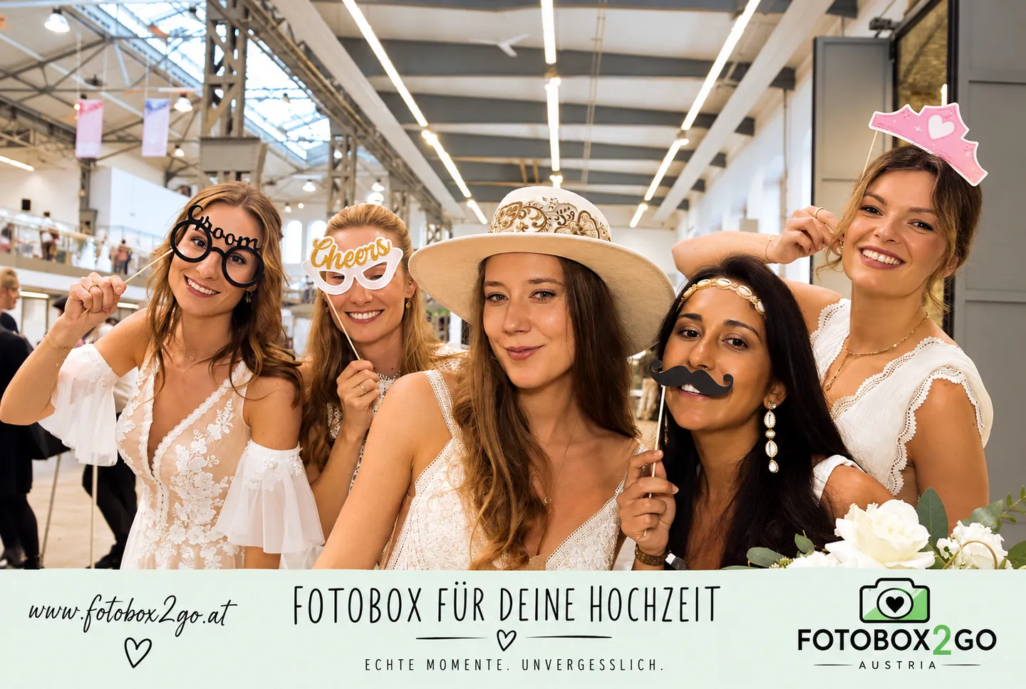 Fünf Frauen posieren mit Hut, Spaßbrillen und Krönchen für ein Erinnerungsfoto.