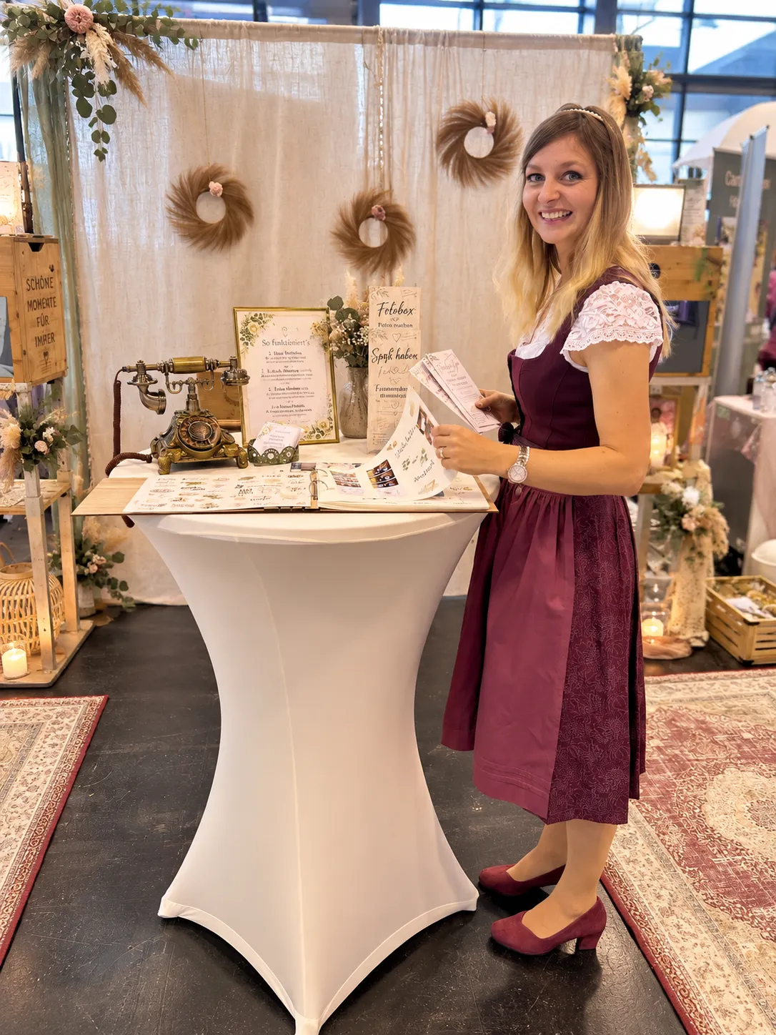 Steffi zeigt ein Fotoalbum am Messestand, neben dem Audio-Gästebuch und Erinnerungsfotos.